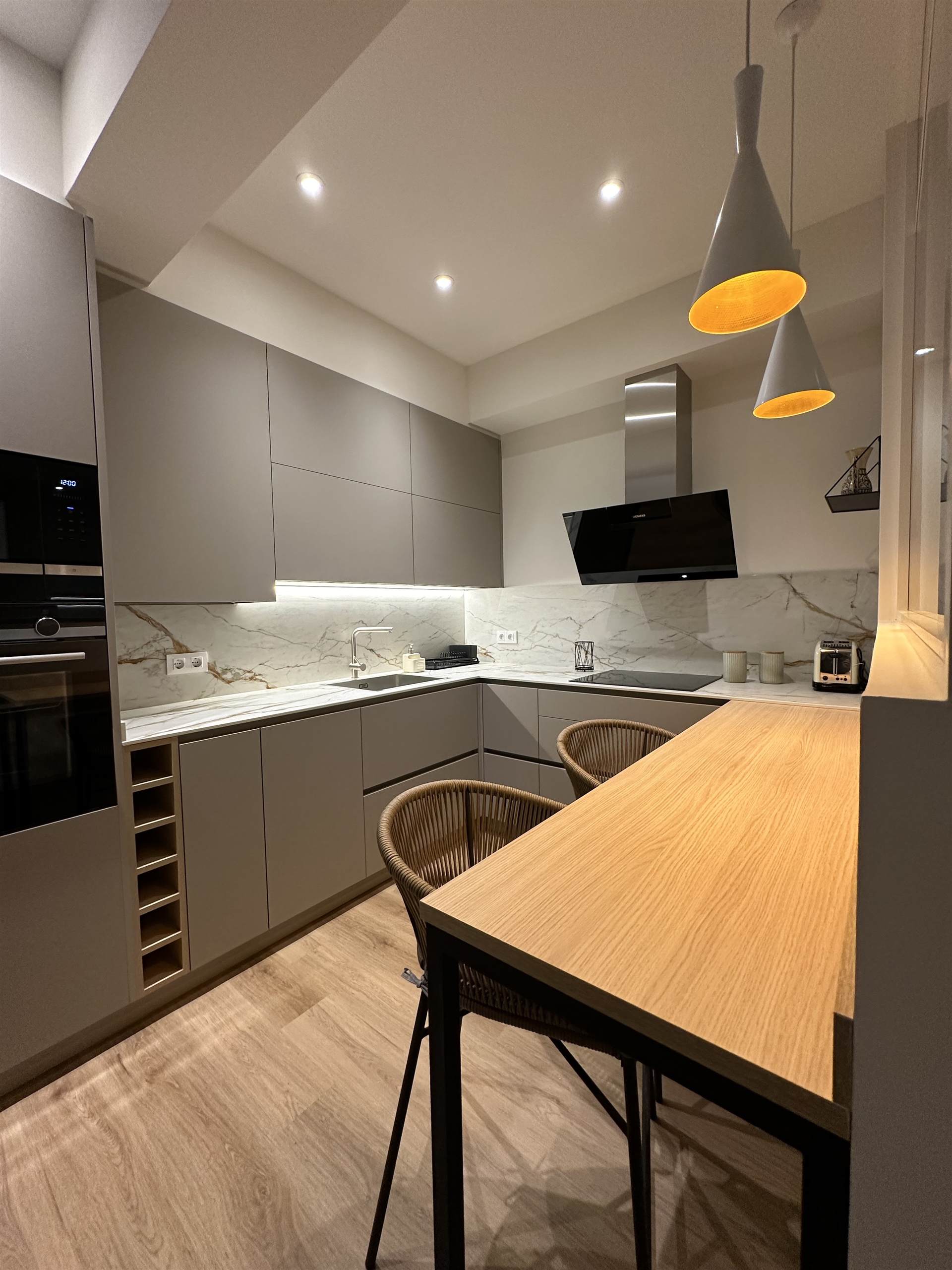 Cocina reformada con isla, campana de acero y luz cálida — proyecto real de Cocinas Orixe