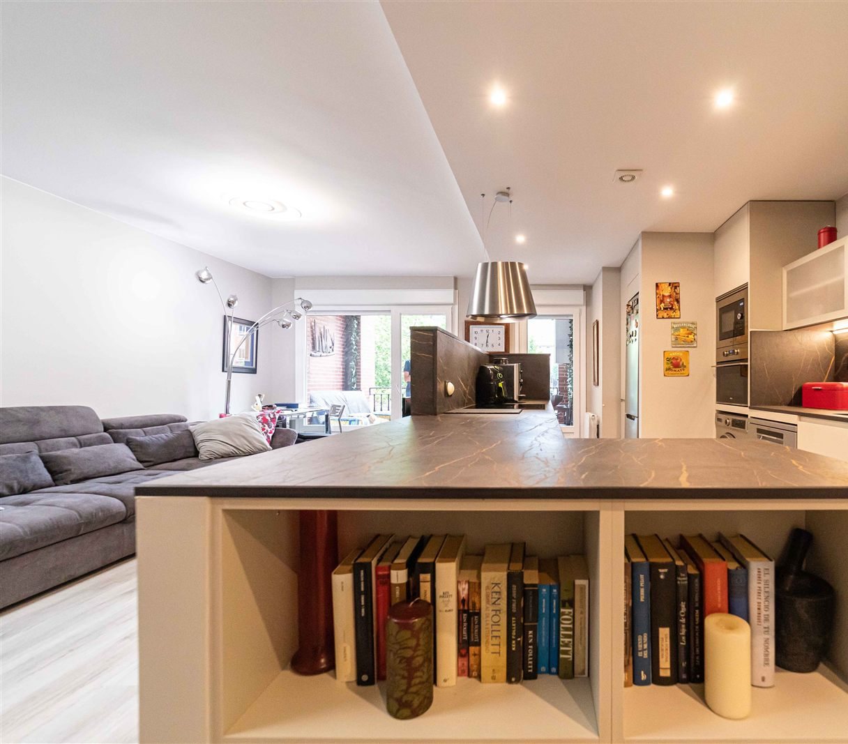 Cocina abierta al salón con librería integrada bajo la isla — proyecto de Cocinas Orixe